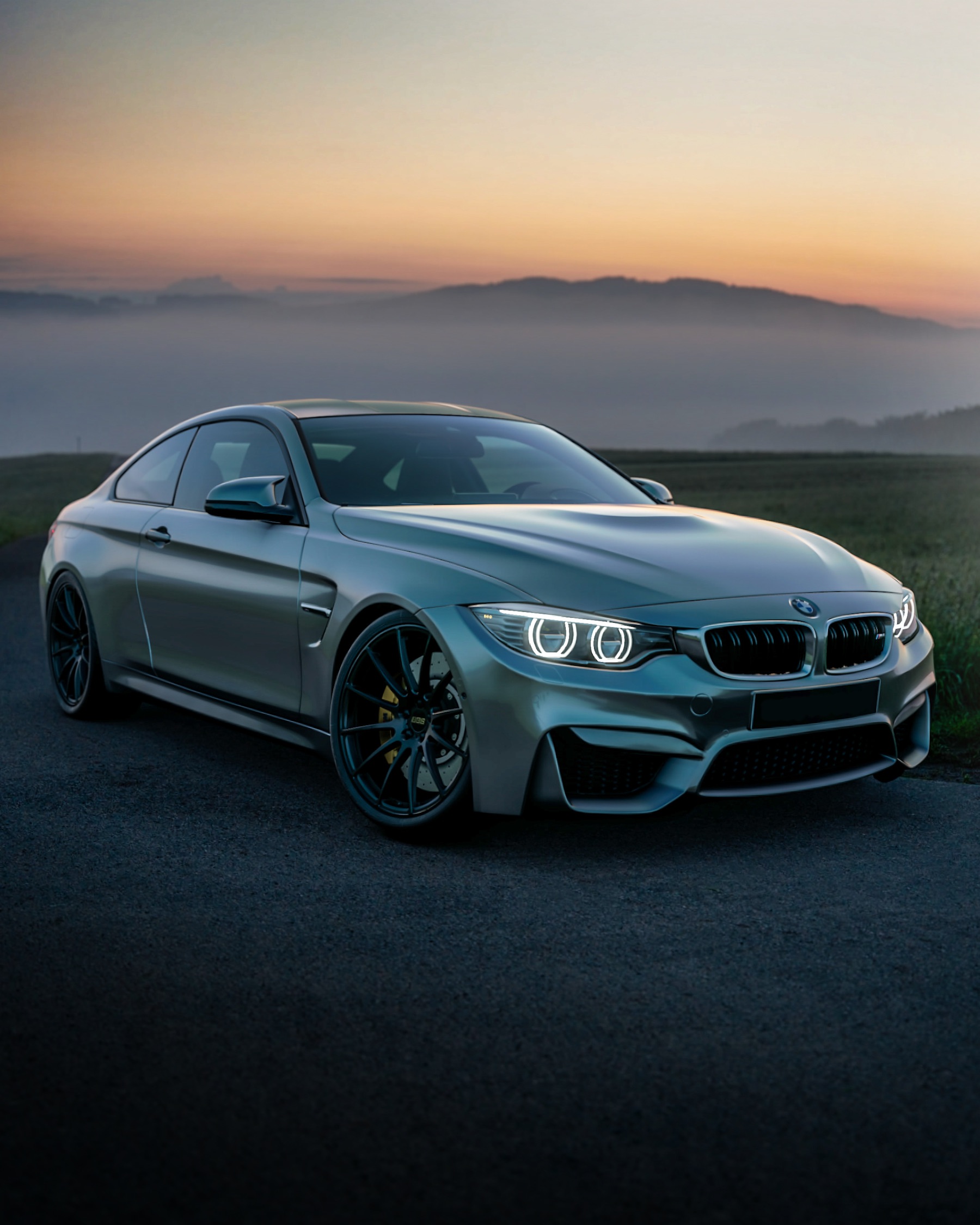 Grey coupe on a mountain road at dusk